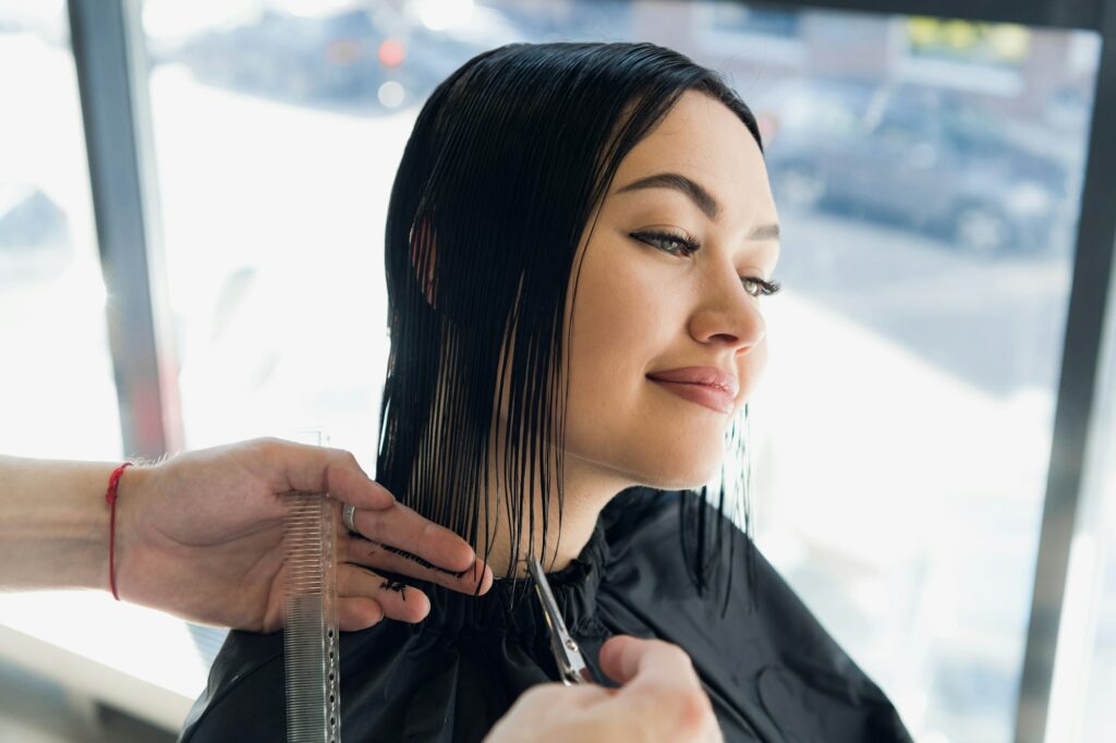Young beautiful woman having her hair cut at the hairdresser's. Enjoying the process of making a