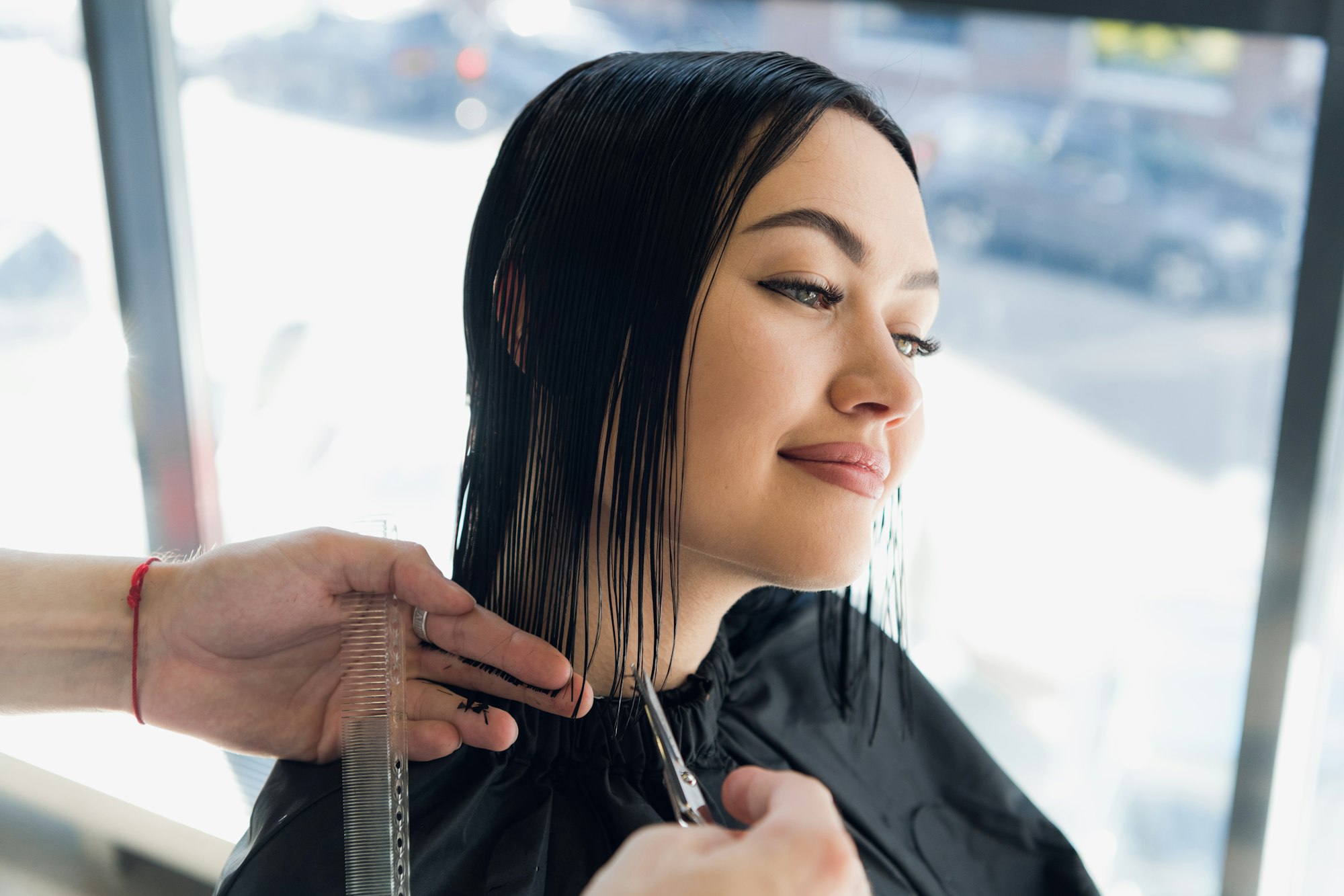 Young beautiful woman having her hair cut at the hairdresser's. Enjoying the process of making a